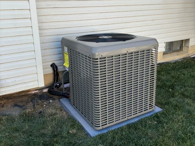Newly installed high-efficiency AC condenser on a concrete pad beside a Toledo home